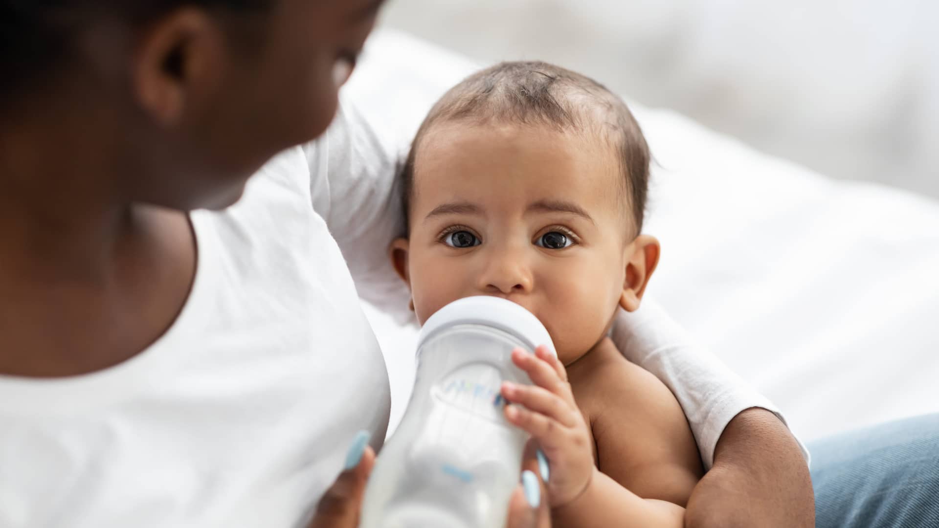 bebe de cuatro meses tomando un biberon con su leche especial