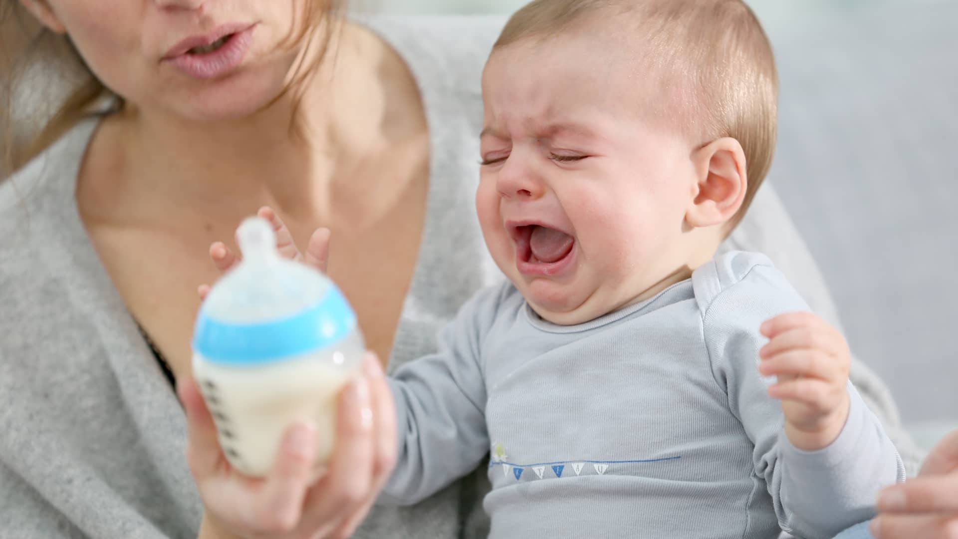 Un bebé llorando enfadado porque no quiere el biberón