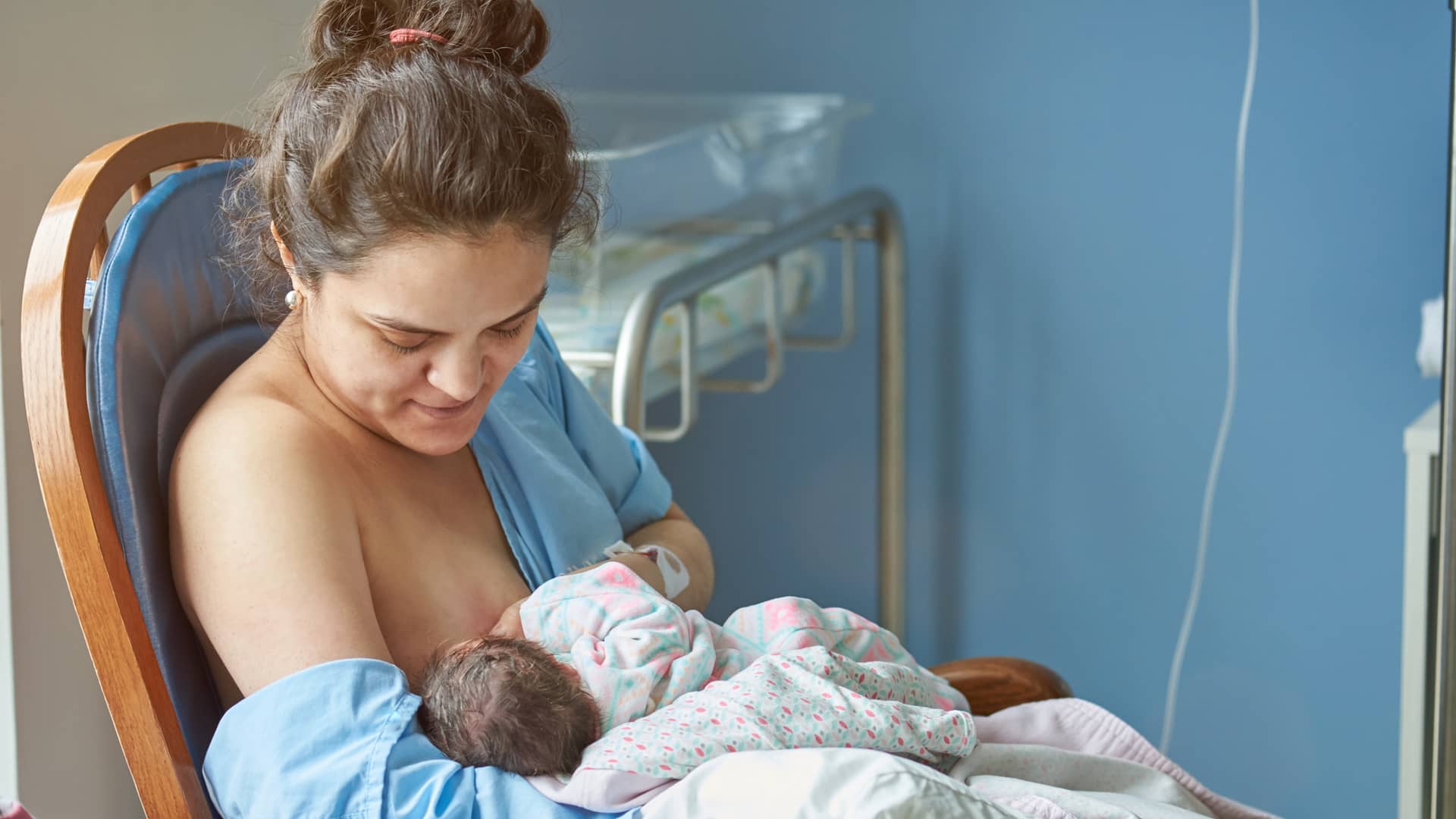 Mujer en el hospital dándole el calostro, que es la primra lactancia materna, a su bebé