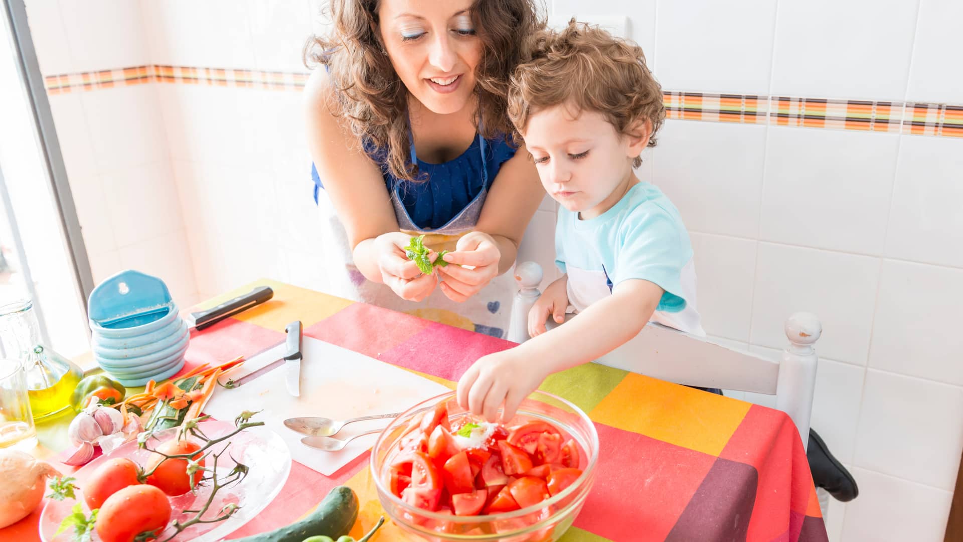 madre cocinando un gazpacho como receta de verano con su hijo en la cocina de casa