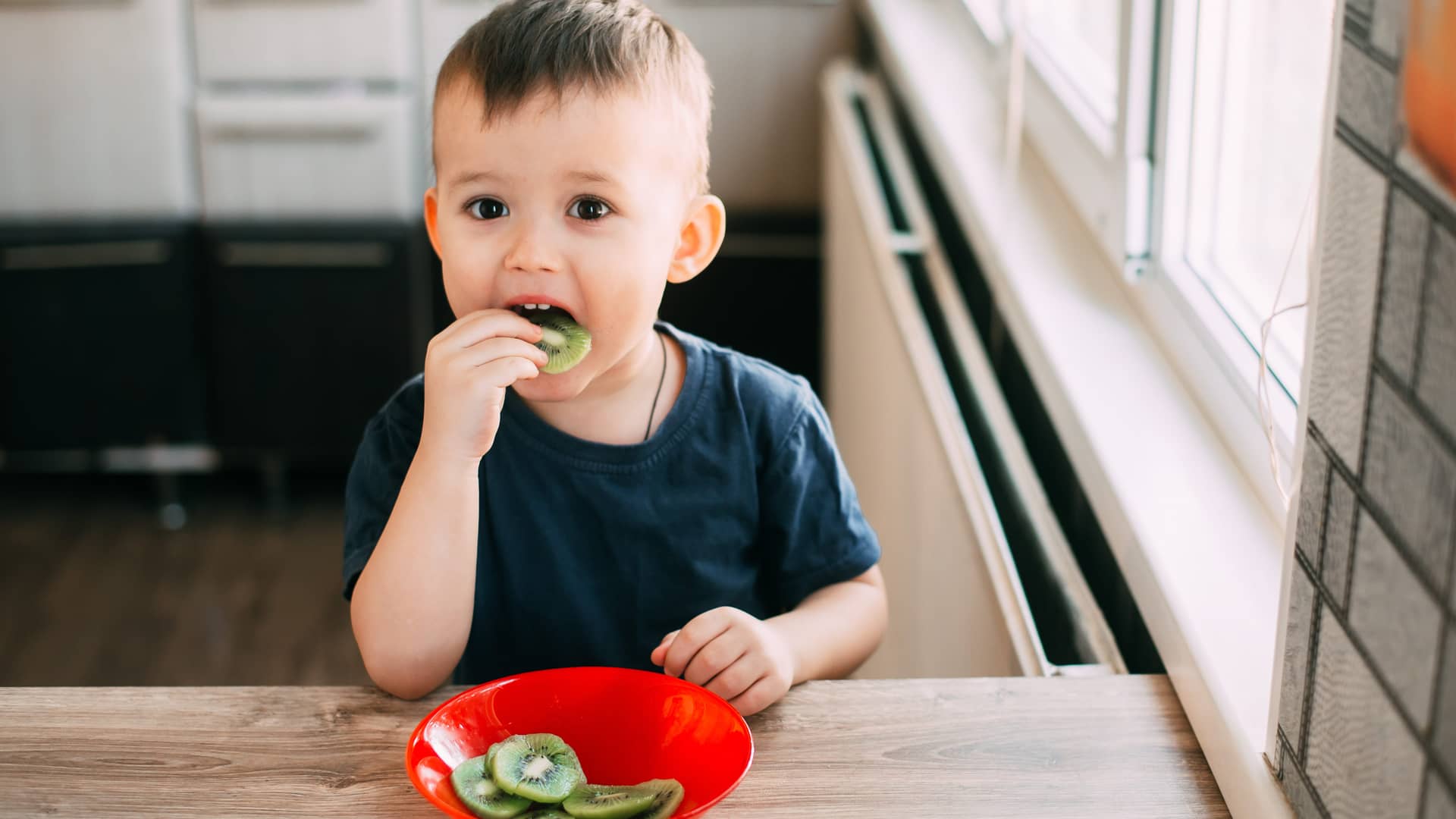 niño pequeño comiendo kiwi porque tiene mucha vitamina c