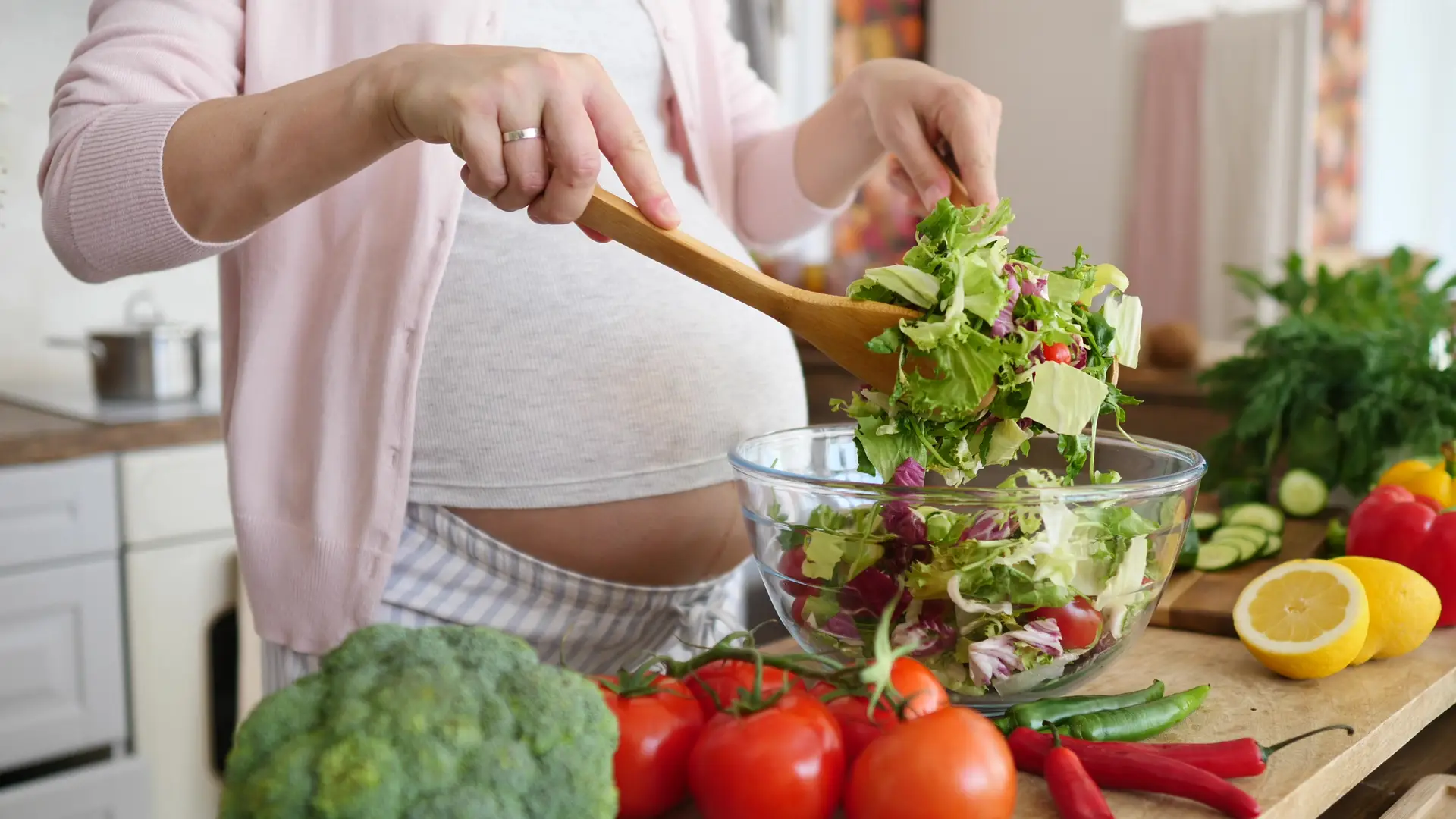 Una mujer embarazada preparnado una comida sana pasa su dieta especifica durante el embarazo Una mujer embarazada preparnado una comida sana pasa su dieta especifica durante el embarazo
