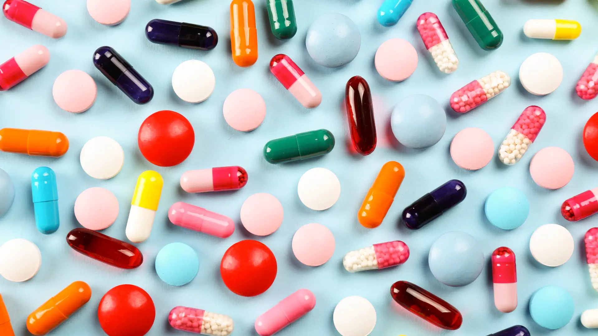 Muchas pastillas de colores sobre un fondo azul para representar como afectan los medicamentos al embarazo