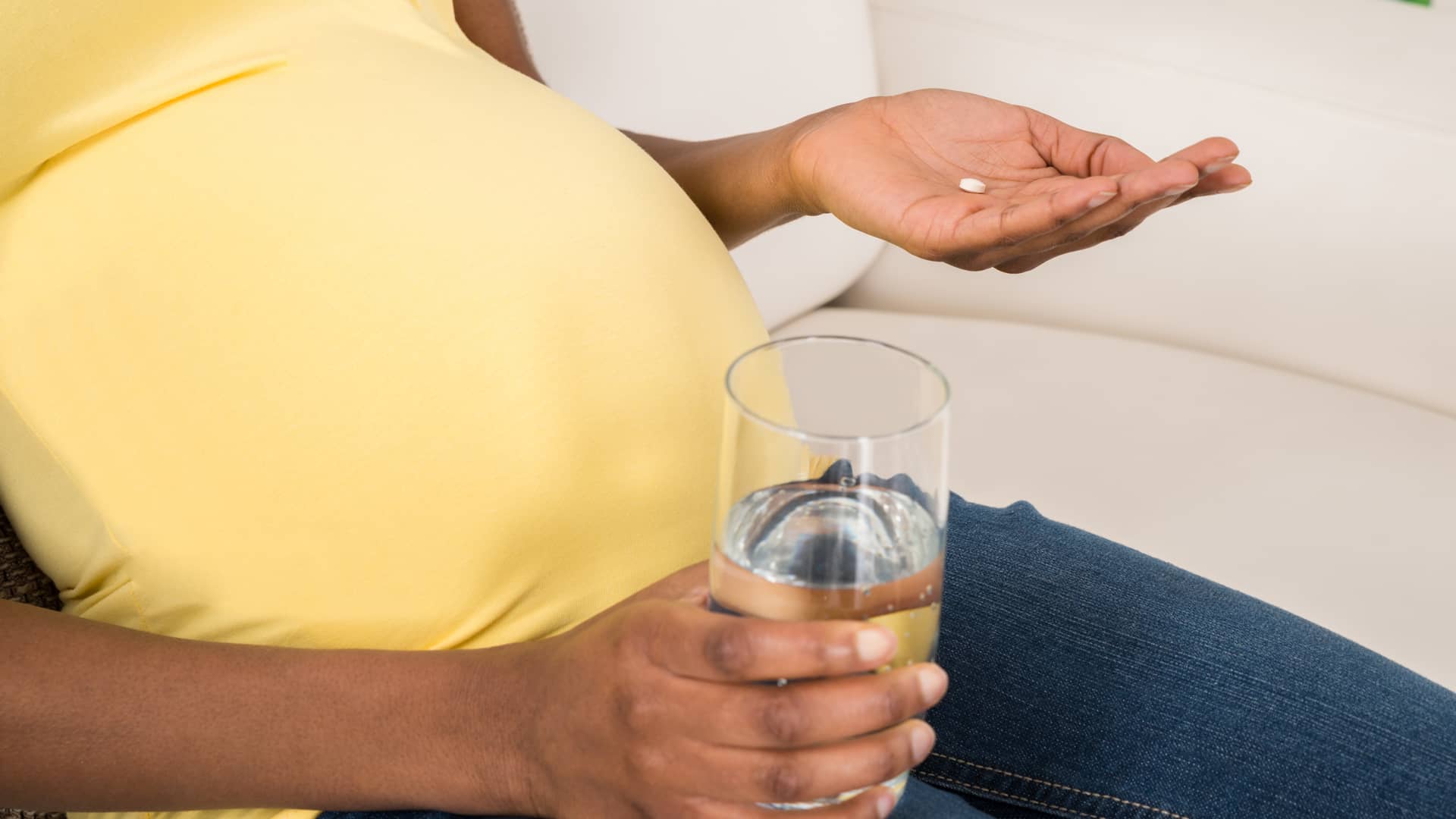 Manos de una embarazada a punto de tomarse un paracetamol para el dolor de cabeza que sufre
