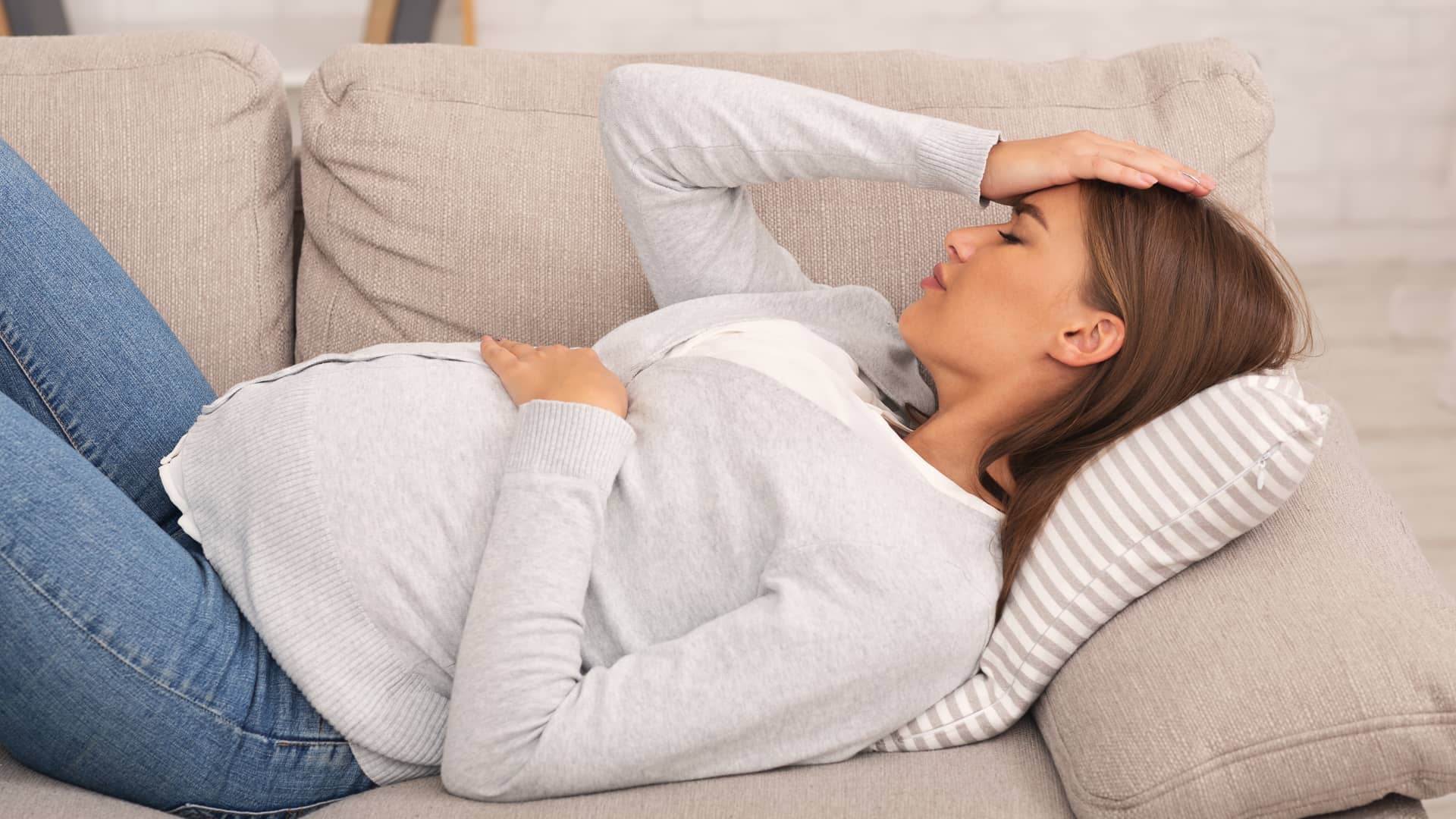 Mujer tumbada por el dolor de barriga que tiene en la semana 17 de embarazo Mujer tumbada por el dolor de barriga que tiene en la semana 17 de embarazo
