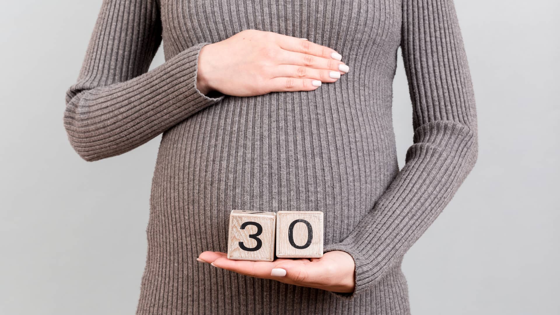Mujer embarazada de 30 semanas tocandose la barriga con las manos