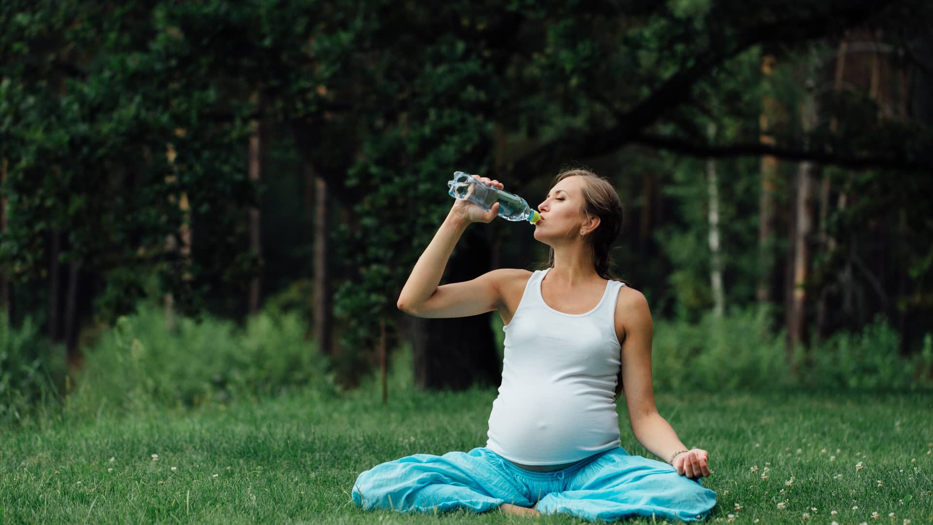 Embarazada de semana 31 bebiendo agua mientras hace yoga
