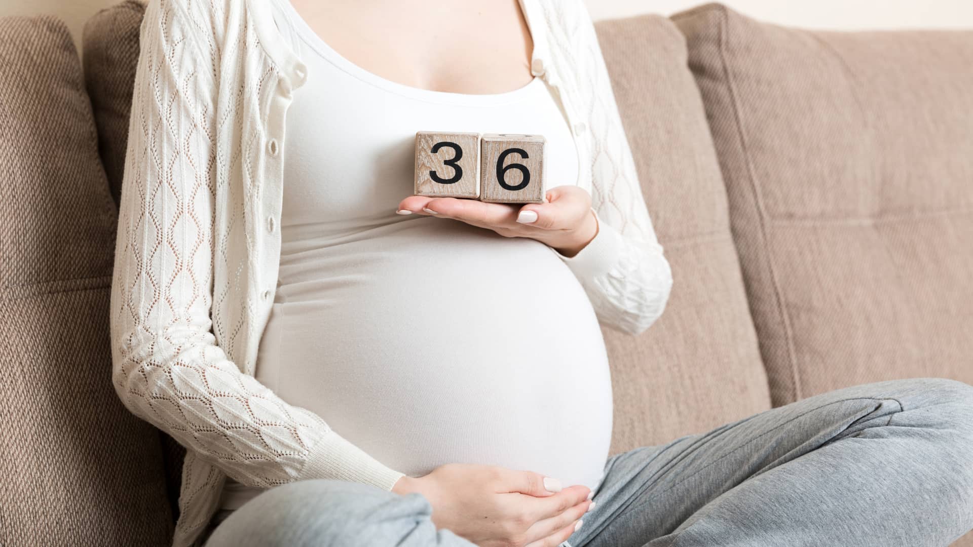 Chica sobre la cama con unos dados representando que está en la semana 36 de embarazo Chica sobre la cama con unos dados representando que está en la semana 36 de embarazo