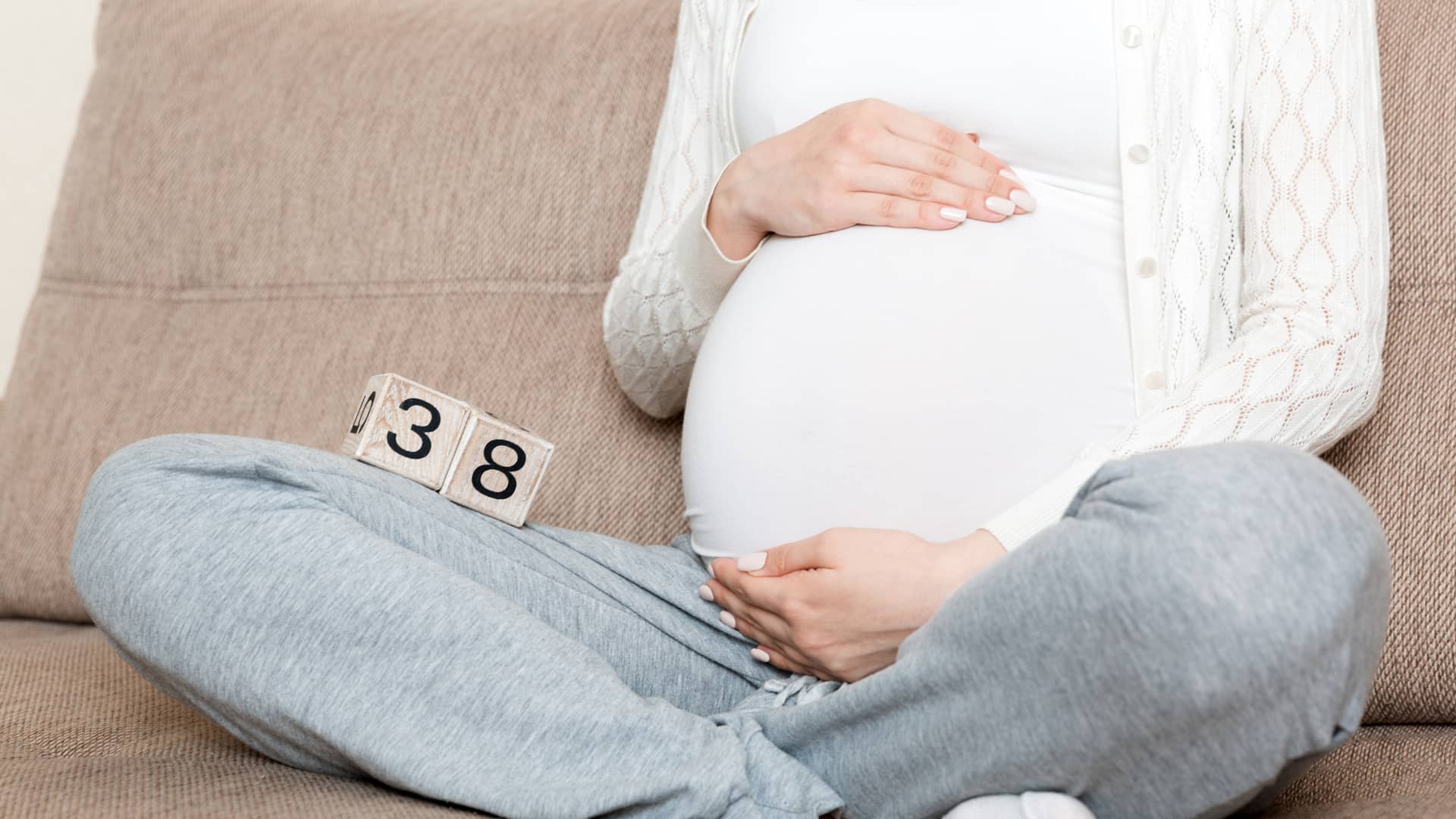 Chica sentada con unos dados de madera que representan que está en la semana 38 de embarazo Chica sentada con unos dados de madera que representan que está en la semana 38 de embarazo