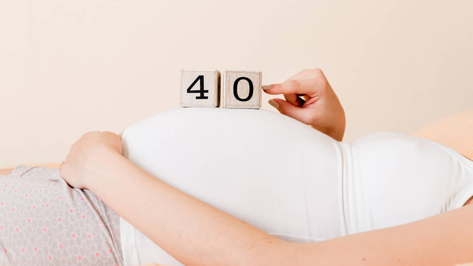 Mujer luce su barriga de 40 semanas de embarazo junto a unos dados que indican los números Mujer luce su barriga de 40 semanas de embarazo junto a unos dados que indican los números