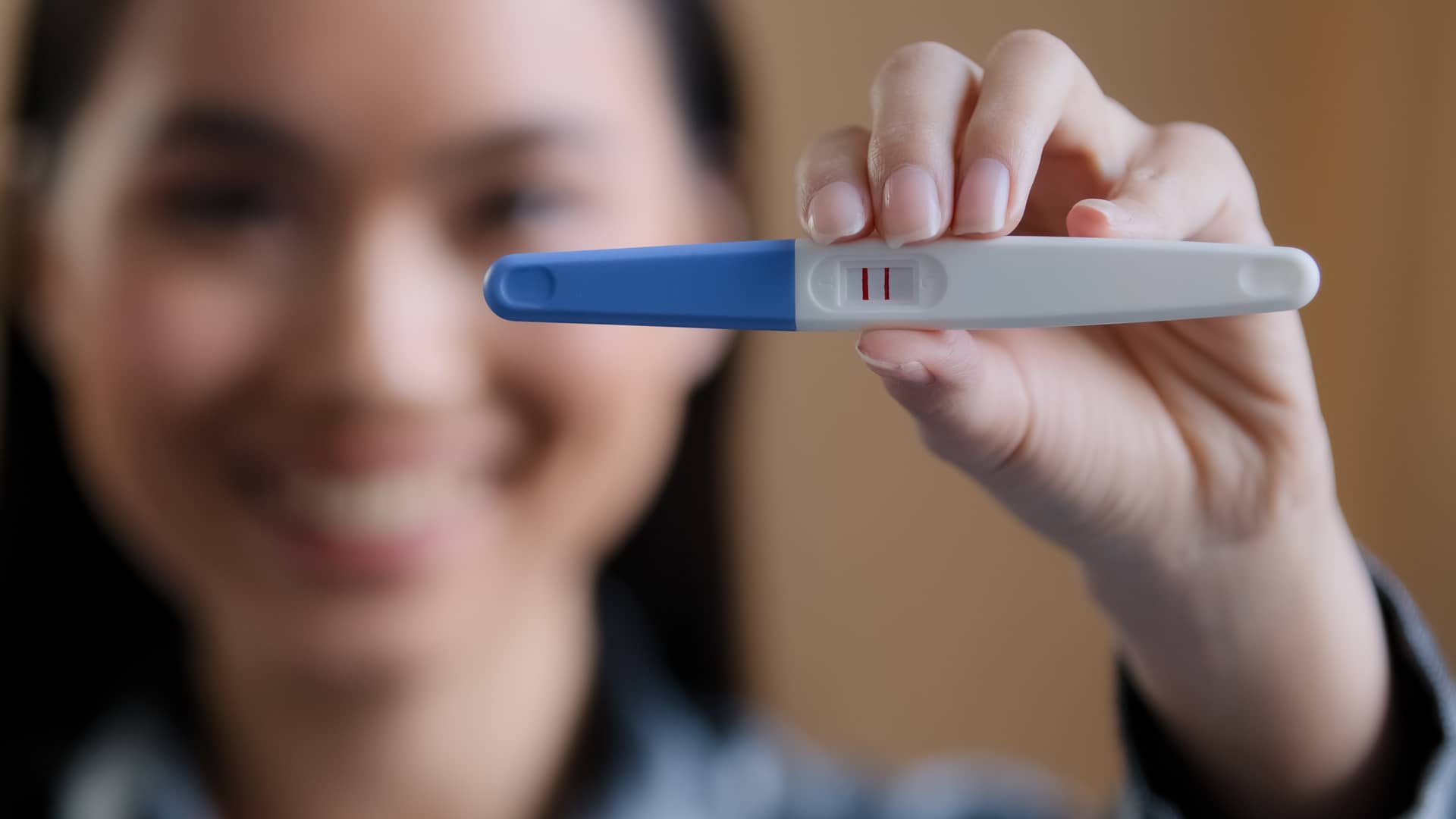 Chica sosteniendo contenta un test de embarazo con dos rayas