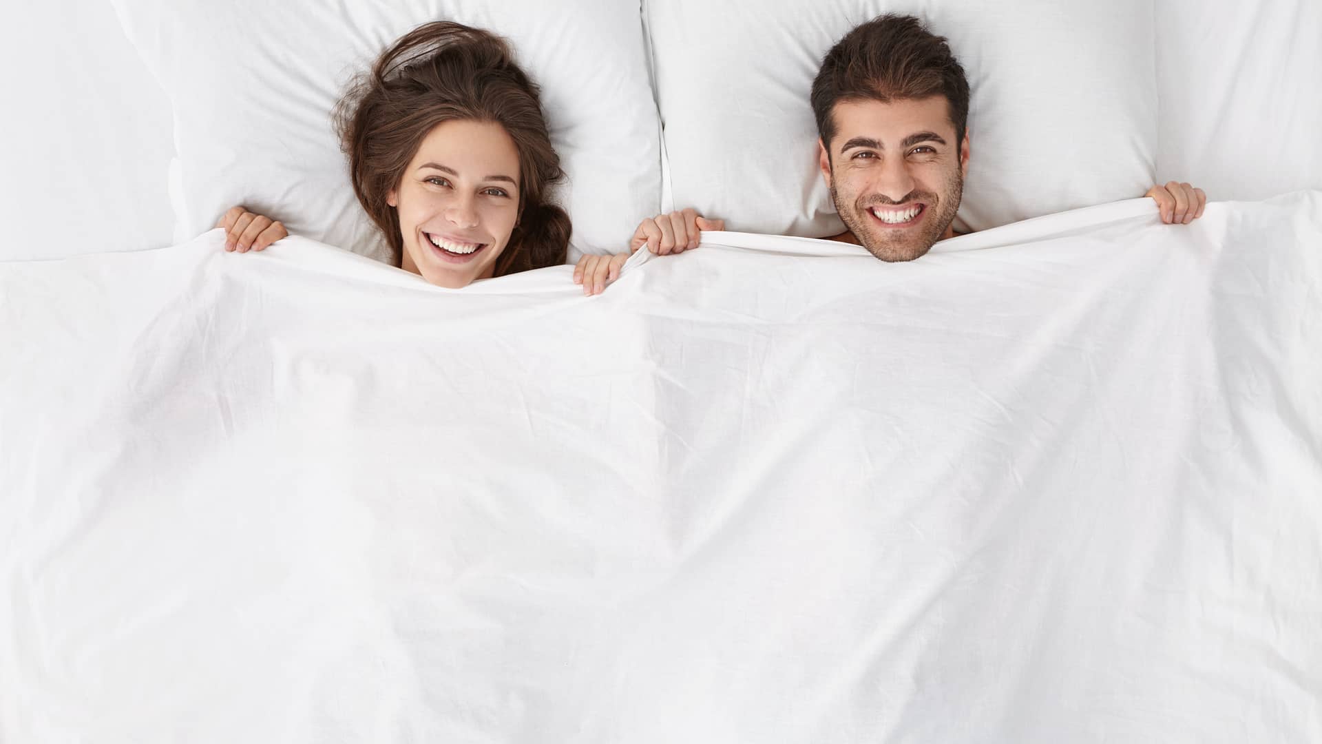 Una pareja contenta en la cama que representa el coito programado