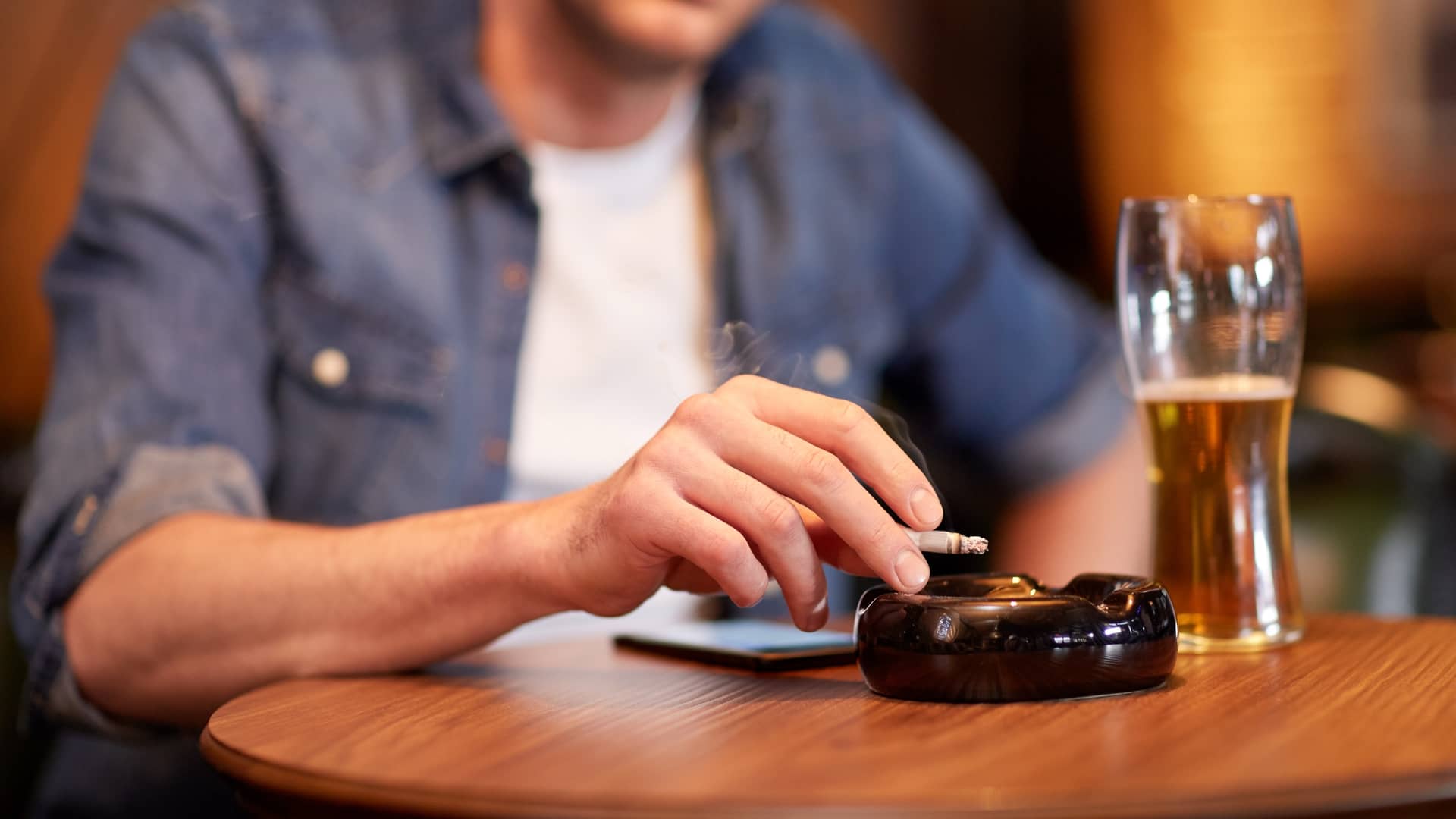 Un chico fumando y bebiendo alcohol que son habitos que aumentan la esterilidad masculina
