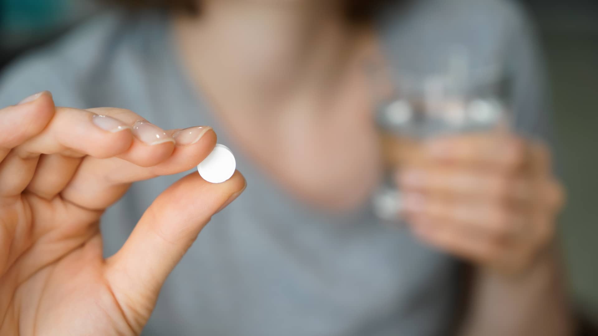 Una mujer a punto de tomarse un comprimido del medicamento Progynova para la estimulación ovárica