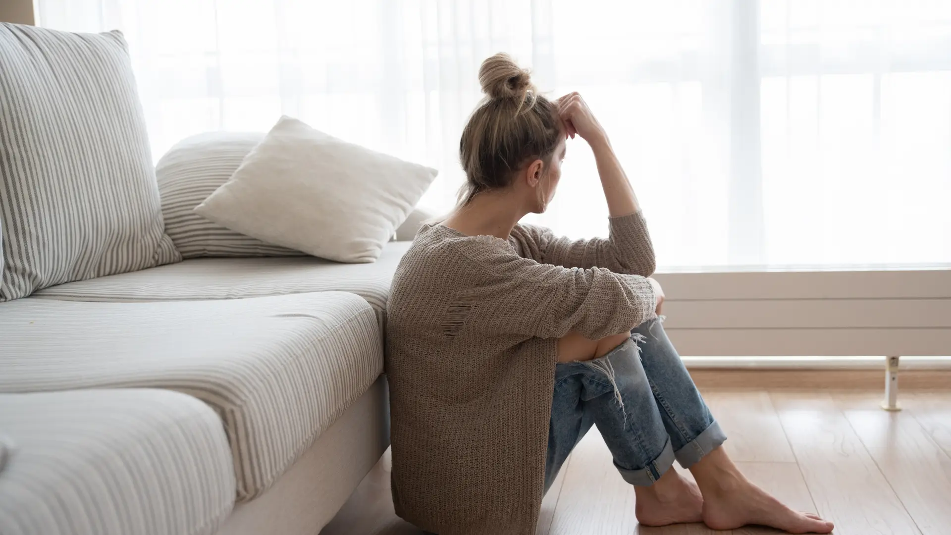 Una chica triste en el sofa de su casa porque tiene algun problema de infertilidad femenina