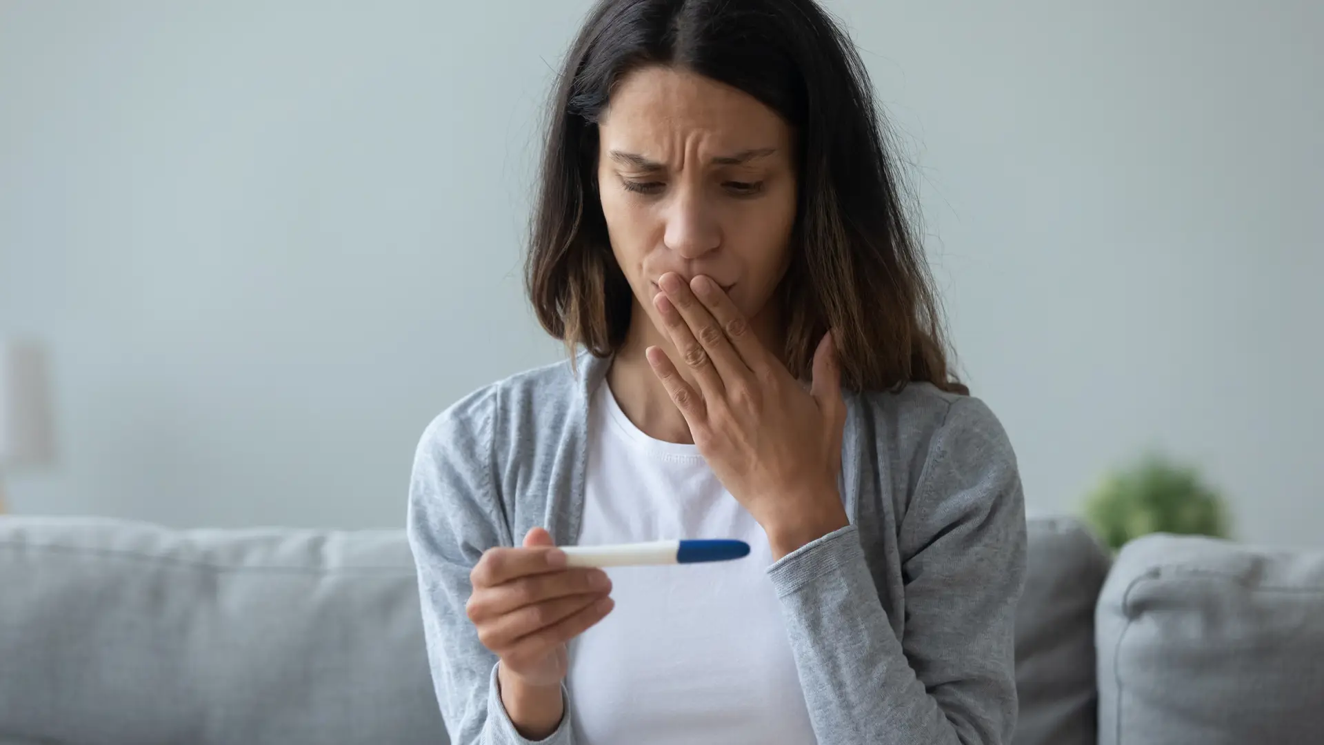 Mujer disgustada mirando un test de embarazo negativo que padece infertidilidad secundaria Mujer disgustada mirando un test de embarazo negativo que padece infertidilidad secundaria