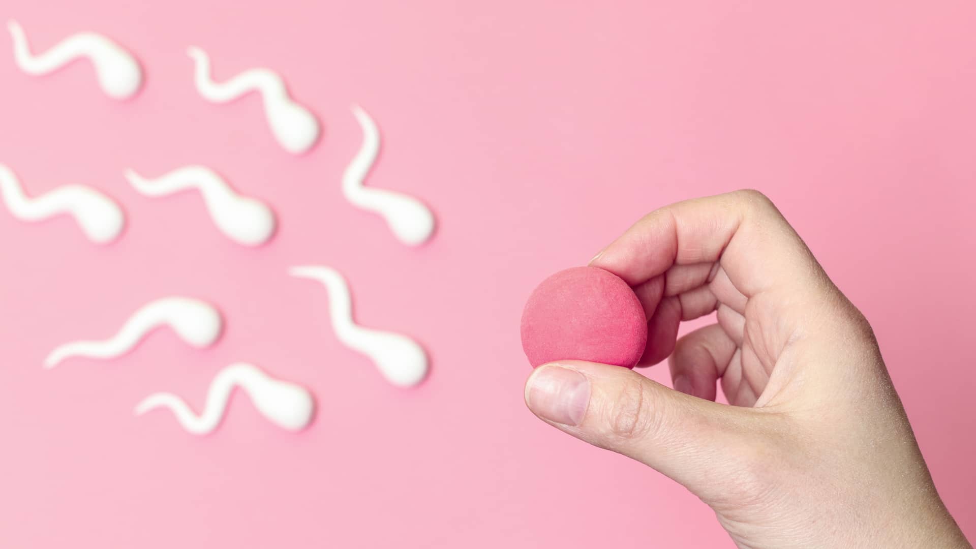 Una mano sujetando unos supuestos ovulo y espermatozoide para representa el proceso de la inseminación arificial