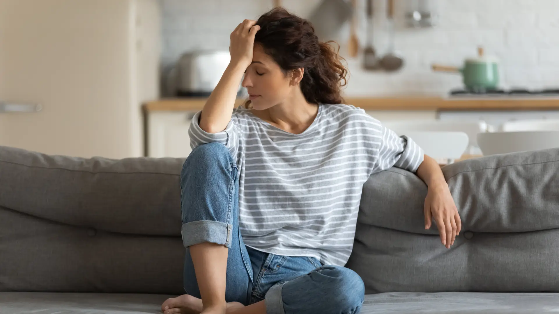 Mujer congesto de cansada en el sofa que es uno de los sintomas de la implantacion embrionaria