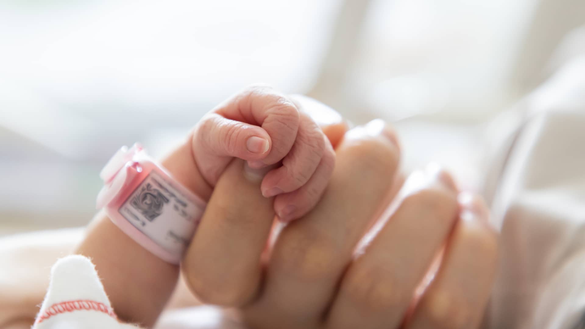 manita de un bebe recien nacido agarrando el dedo de su madre por la alta demanda que tiene con ella