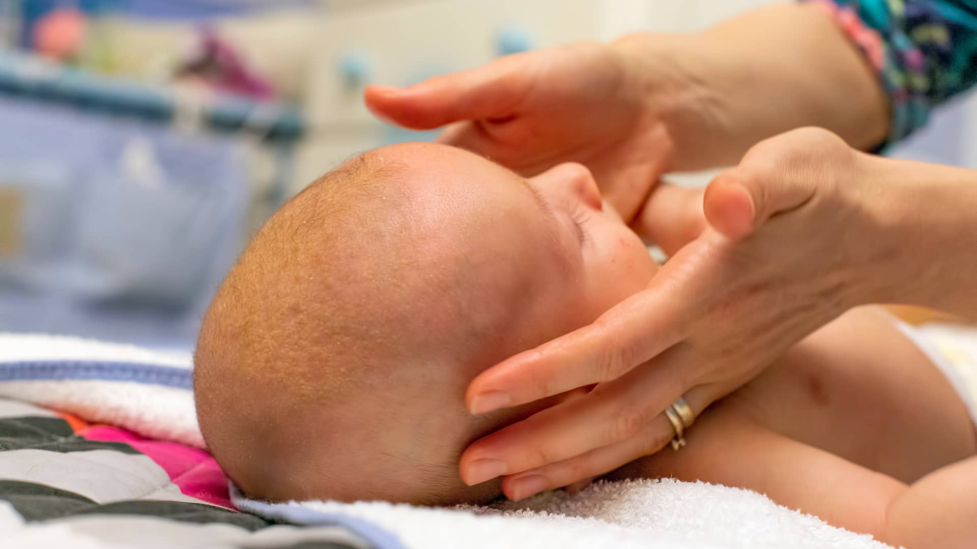 mama tocando la cabeza de su bebe para medir el percentil de la cabeza