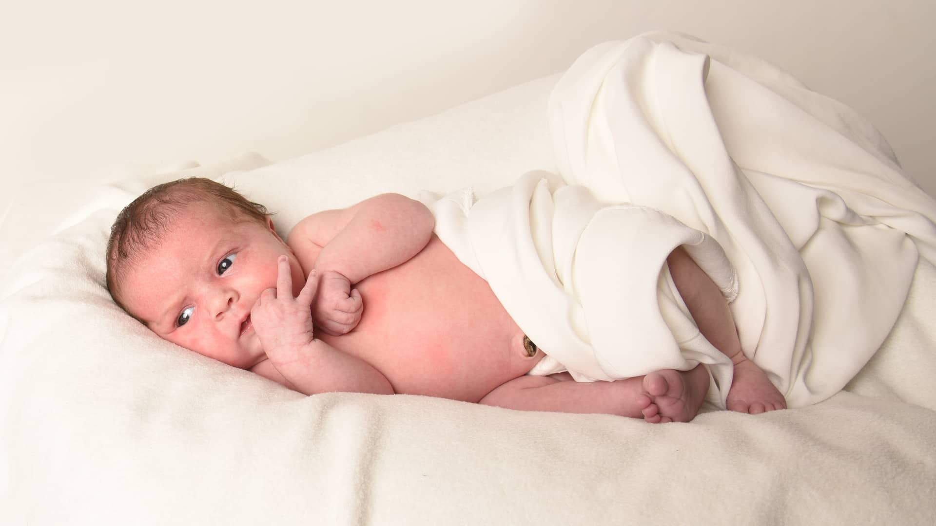un niño bebe de 2 meses tumbado sobre unas sabanas un niño bebe de 2 meses tumbado sobre unas sabanas