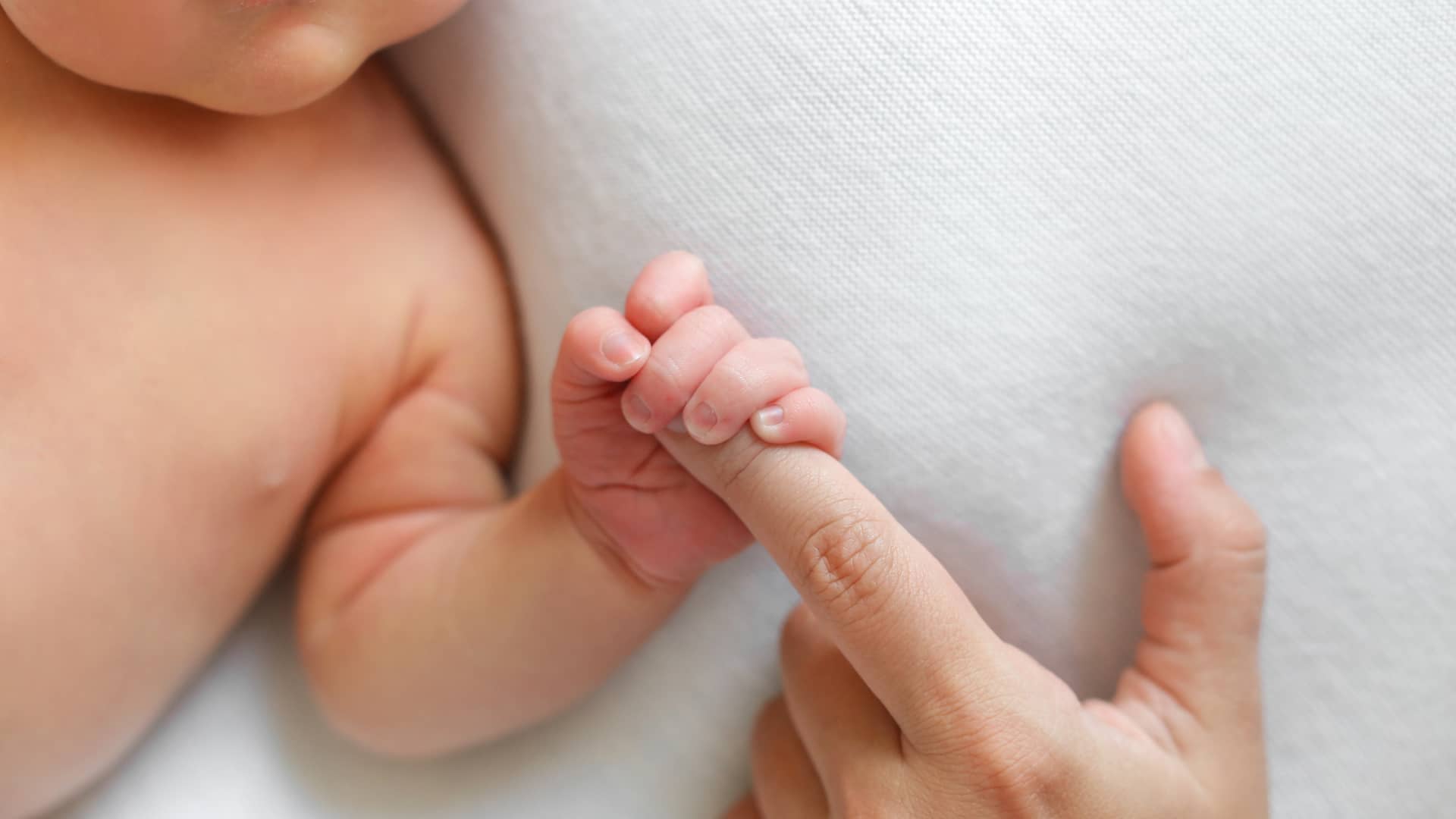 mano de un bebe de 5 meses agarrando un dedo de la mano de su mama