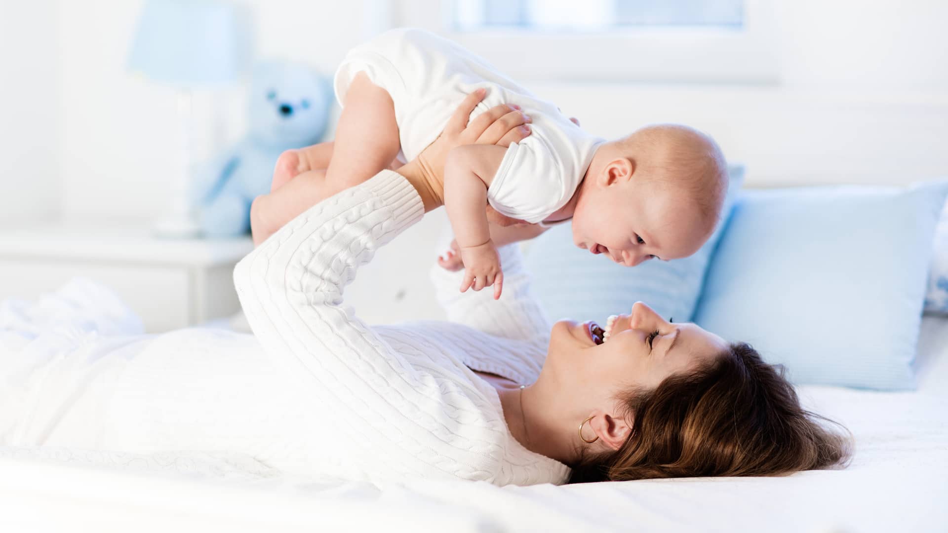 una mama levantando a su bebe de 7 meses mientras juegan tumbada en la cama una mama levantando a su bebe de 7 meses mientras juegan tumbada en la cama