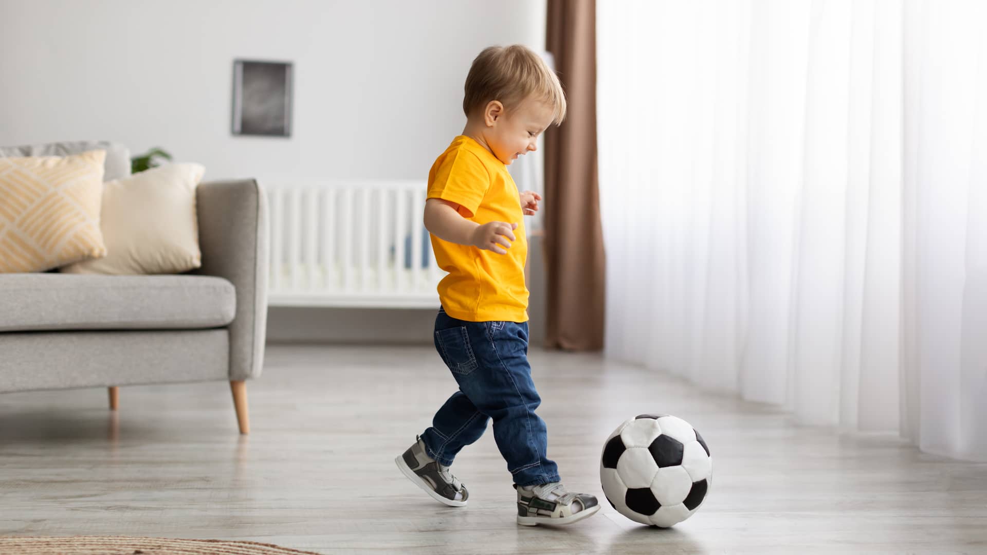 Un niño peuqeño de 12 meses jugando a la pelota para su estimulación temprana 