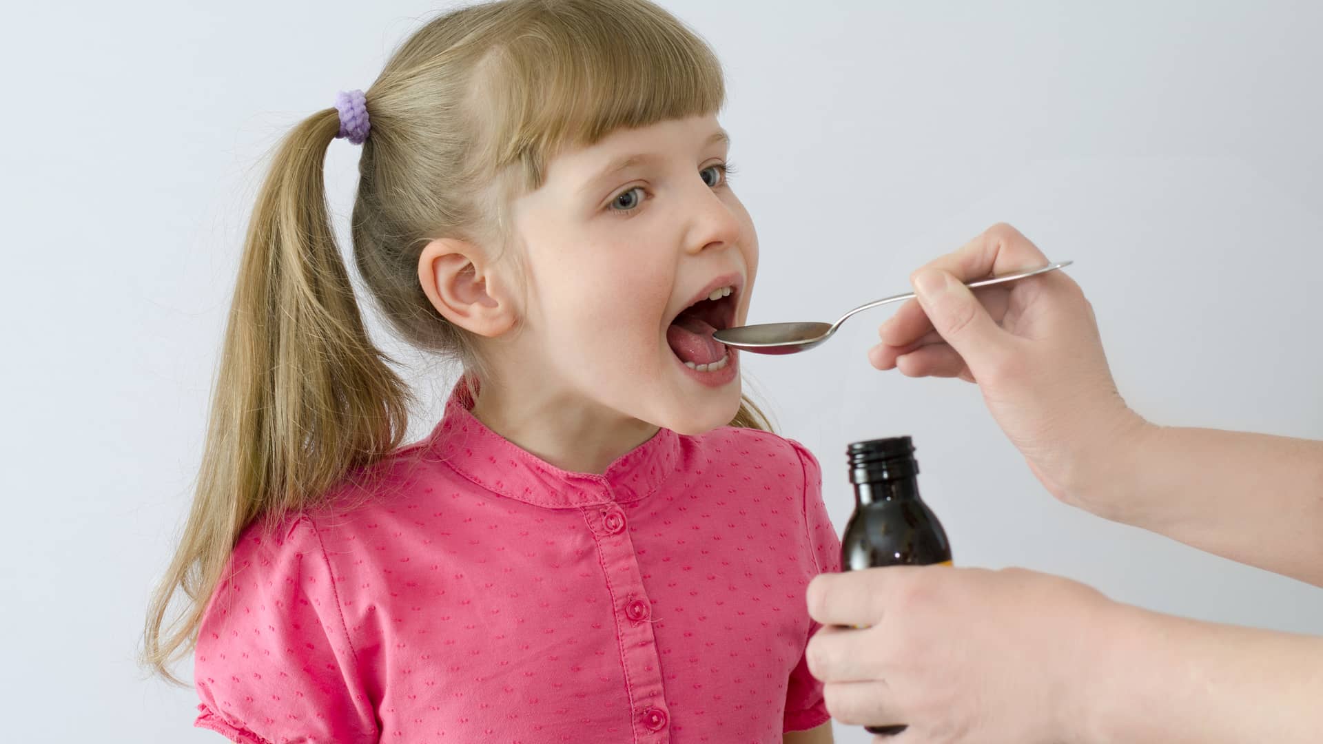 una mama dandole con una cuchara un jarabe a su hija que es un antihistaminico especial para la alergia una mama dandole con una cuchara un jarabe a su hija que es un antihistaminico especial para la alergia
