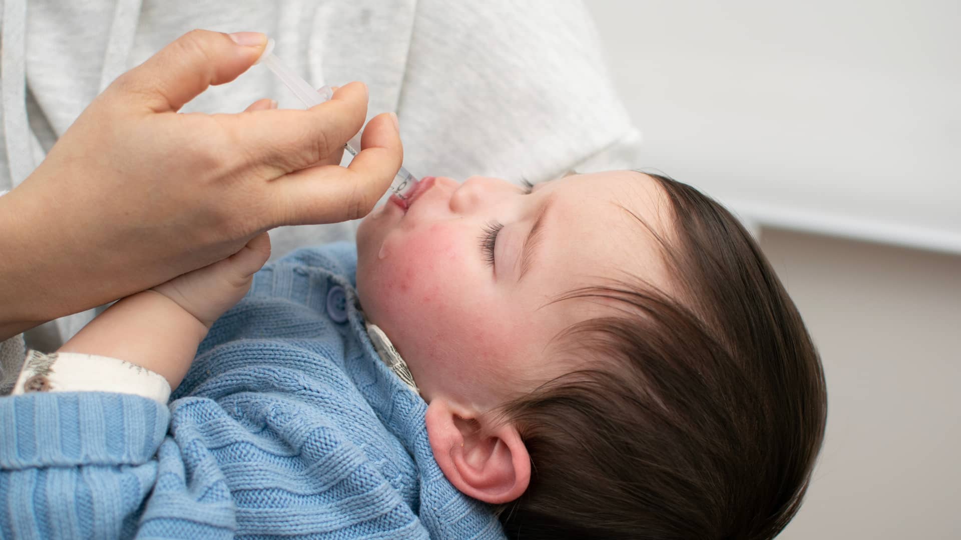 una mama dandole a su hijo un jarabe de desloratadina para acabar con la alergia de su bebe