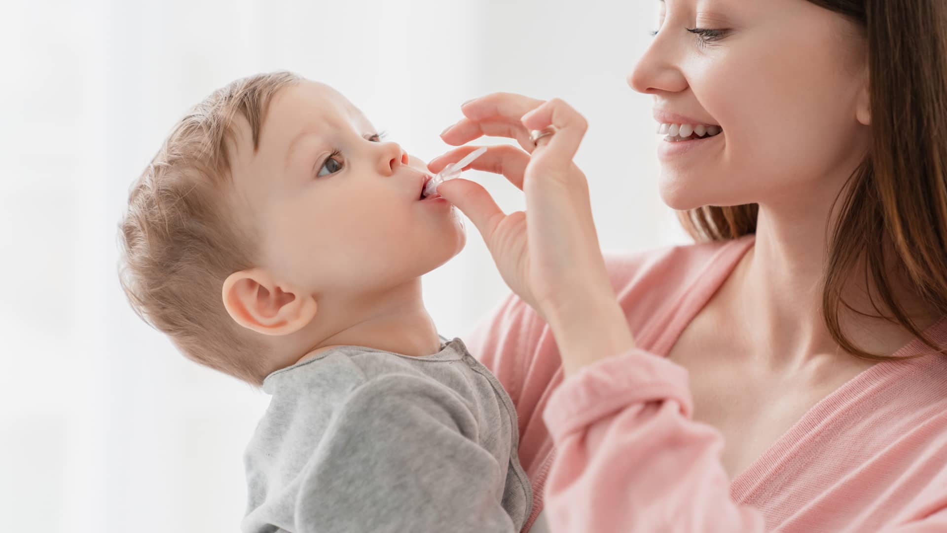 una mama administrando a su hijo la cantidad en gotas que debe tomar de ibuprofeno