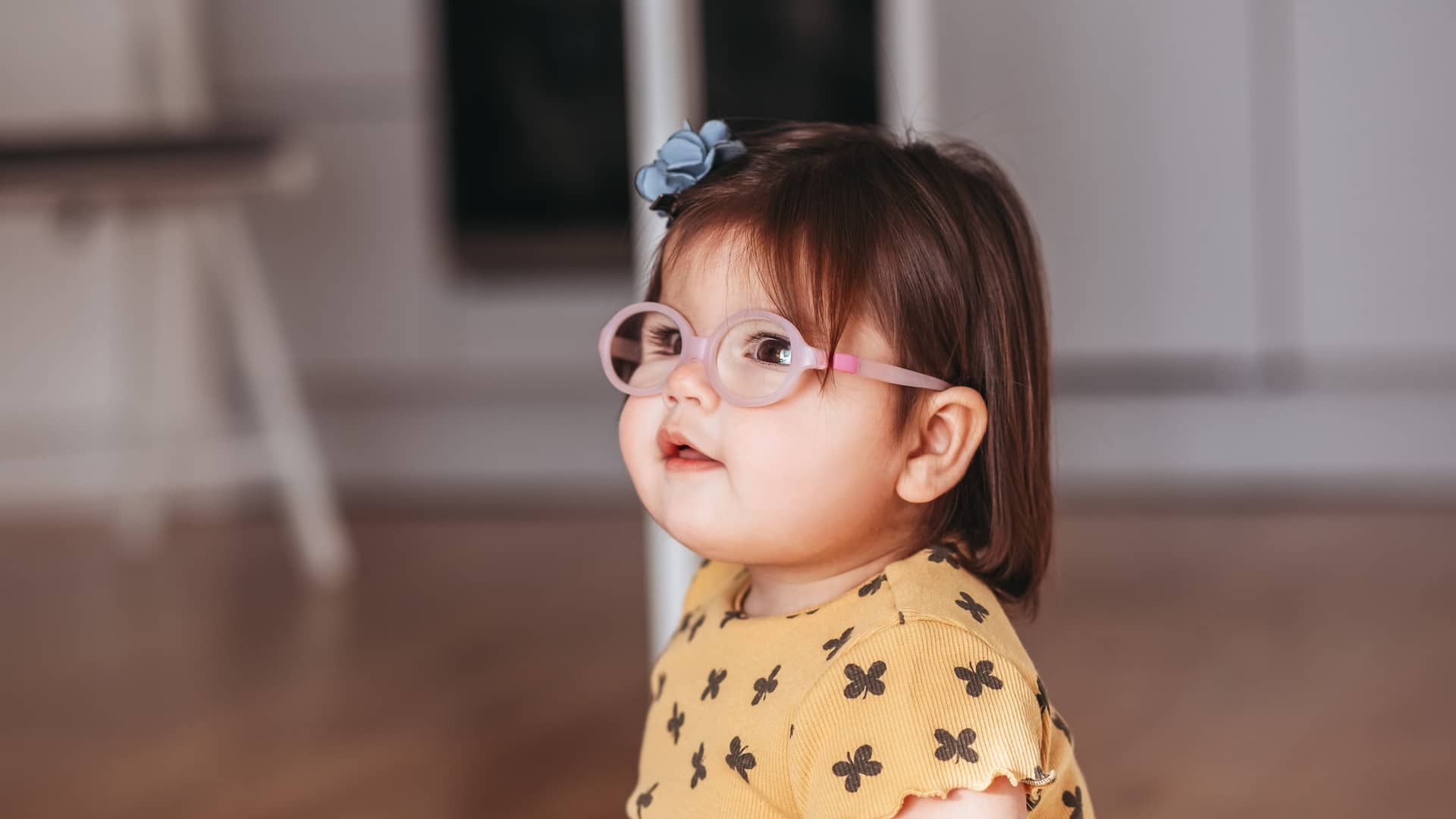 niña pequeña con gafas mirando hacia arriba porque tiene astigmatismo infantil por la curvatura de sus ojos