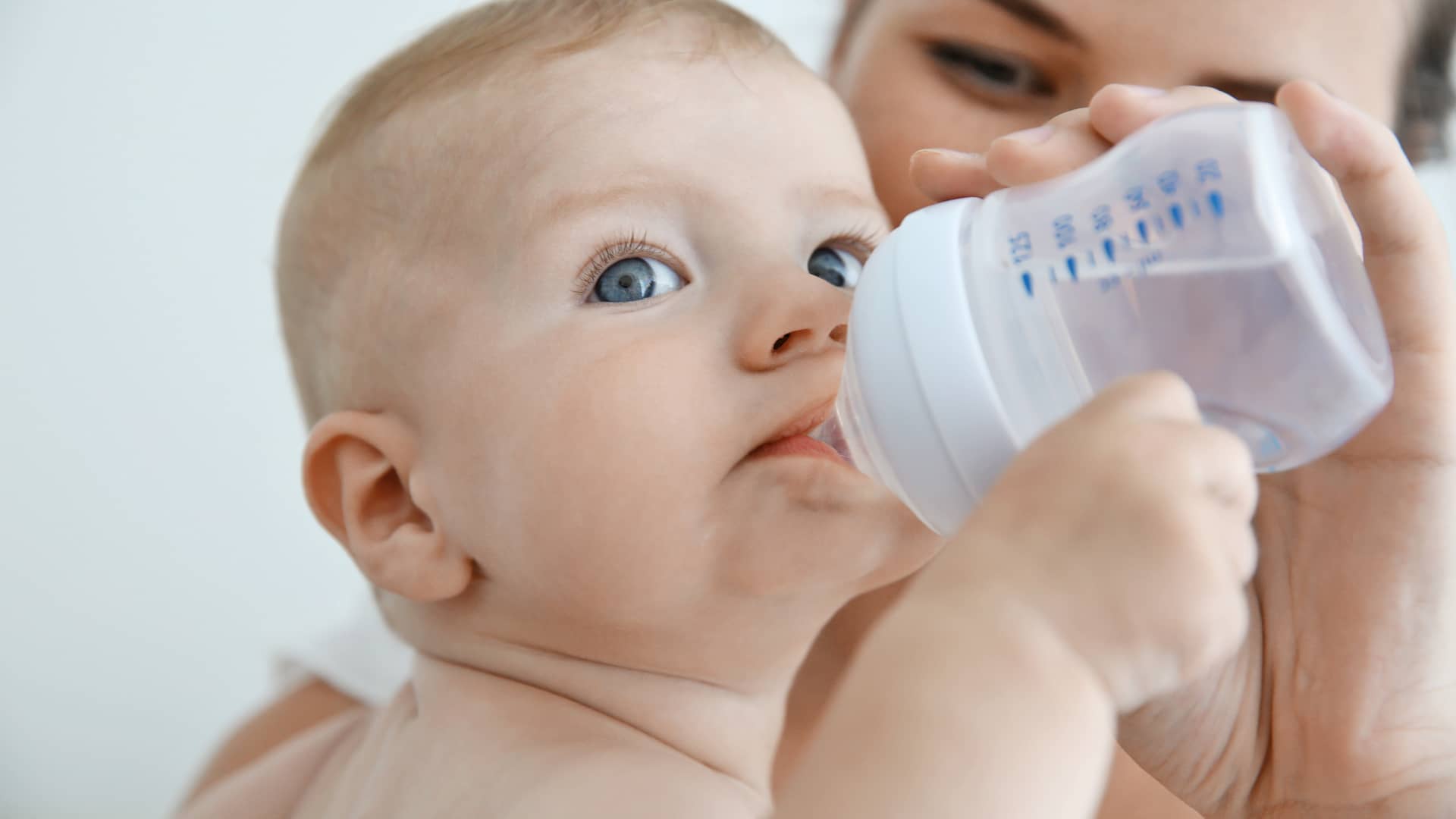 bebé bebiendo agua de un biberon que le da su madre porque tiene mucha sed por la diabetes que padece