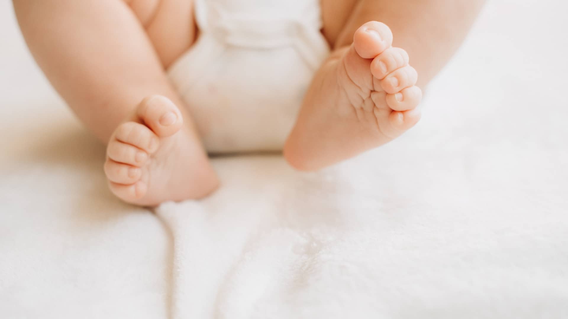 piernas de un bebe tumbado enuna cama para explicar lo que es la displastia de cadera en bebés piernas de un bebe tumbado enuna cama para explicar lo que es la displastia de cadera en bebés
