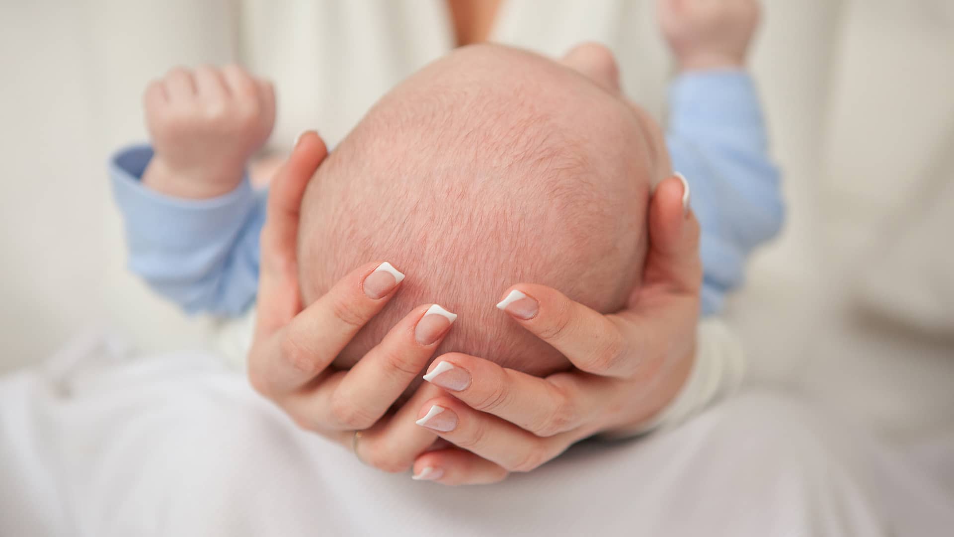 manos de una mama sujetando con cuidado la cabeza de su hijo con hidrocefalia manos de una mama sujetando con cuidado la cabeza de su hijo con hidrocefalia