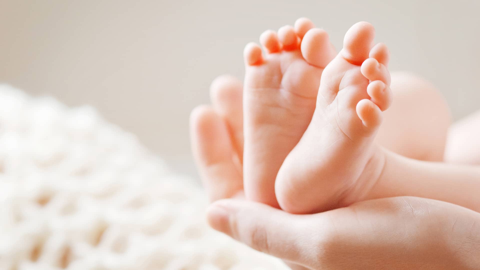 mano de una mama sujetando los pies sanos de su bebe que no tiene hongos