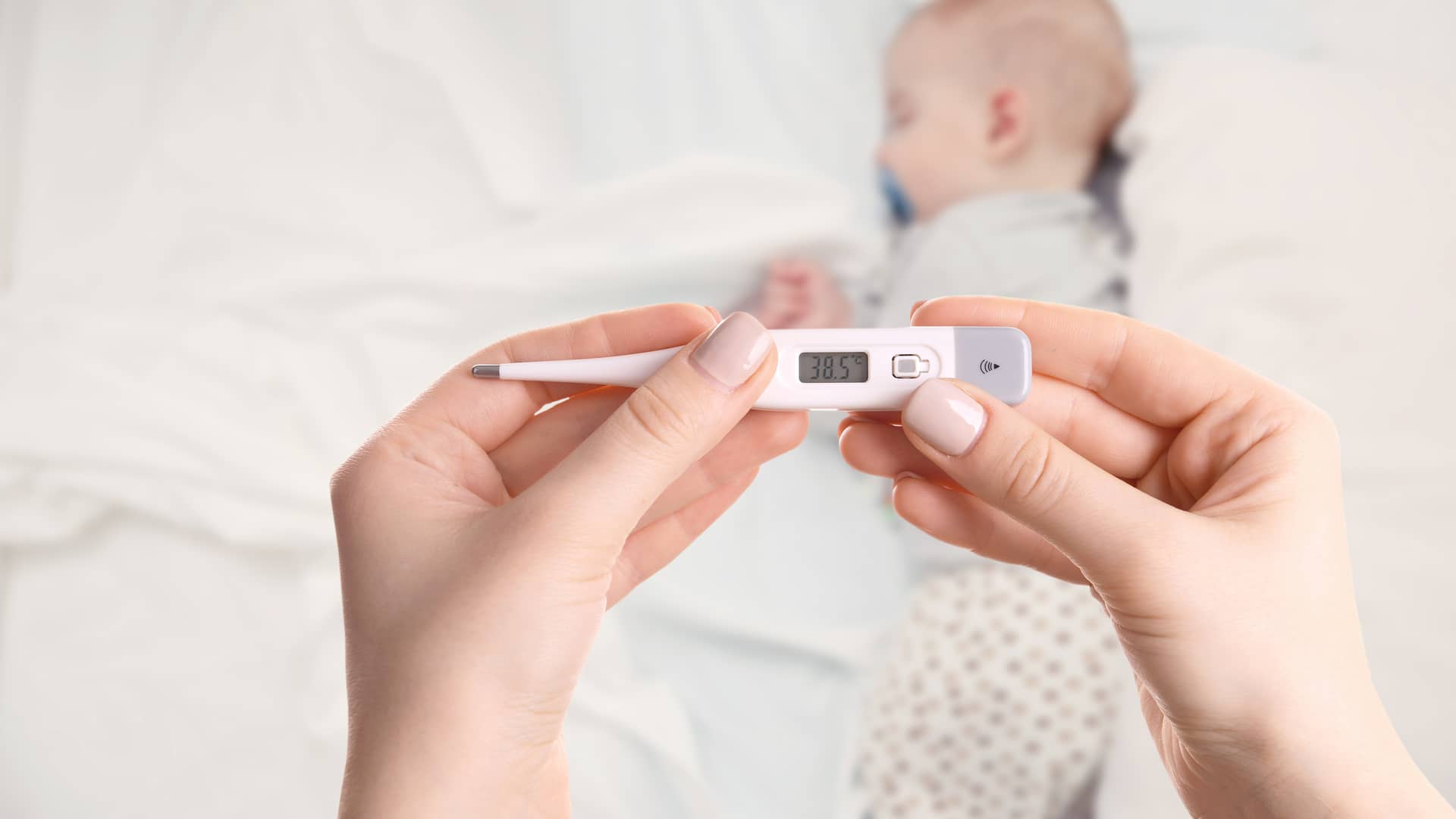 manos de una mama sujetando un termometro con valores de fiebre que acaba de poner a su bebe que tiene infeccion de orina manos de una mama sujetando un termometro con valores de fiebre que acaba de poner a su bebe que tiene infeccion de orina