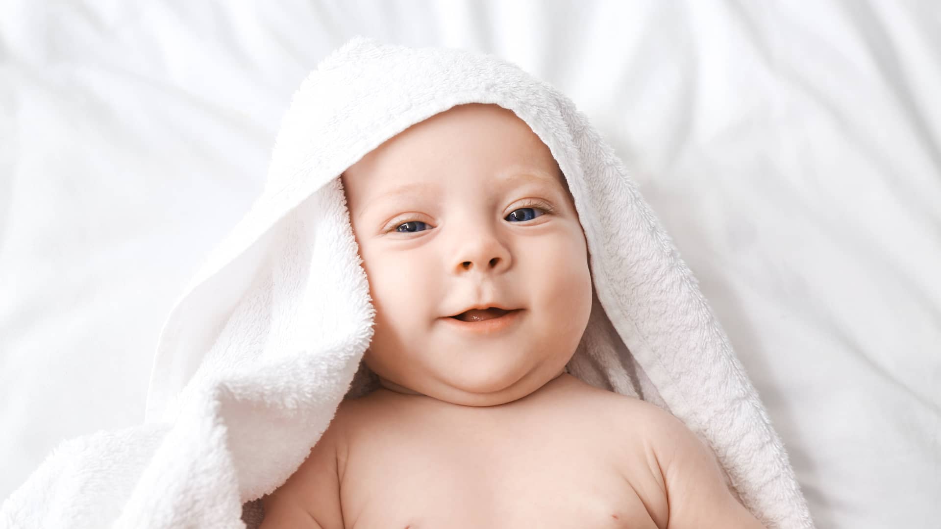 Bebé recién salido de la ducha sonriendo y mirando a cámara porque empieza a ver