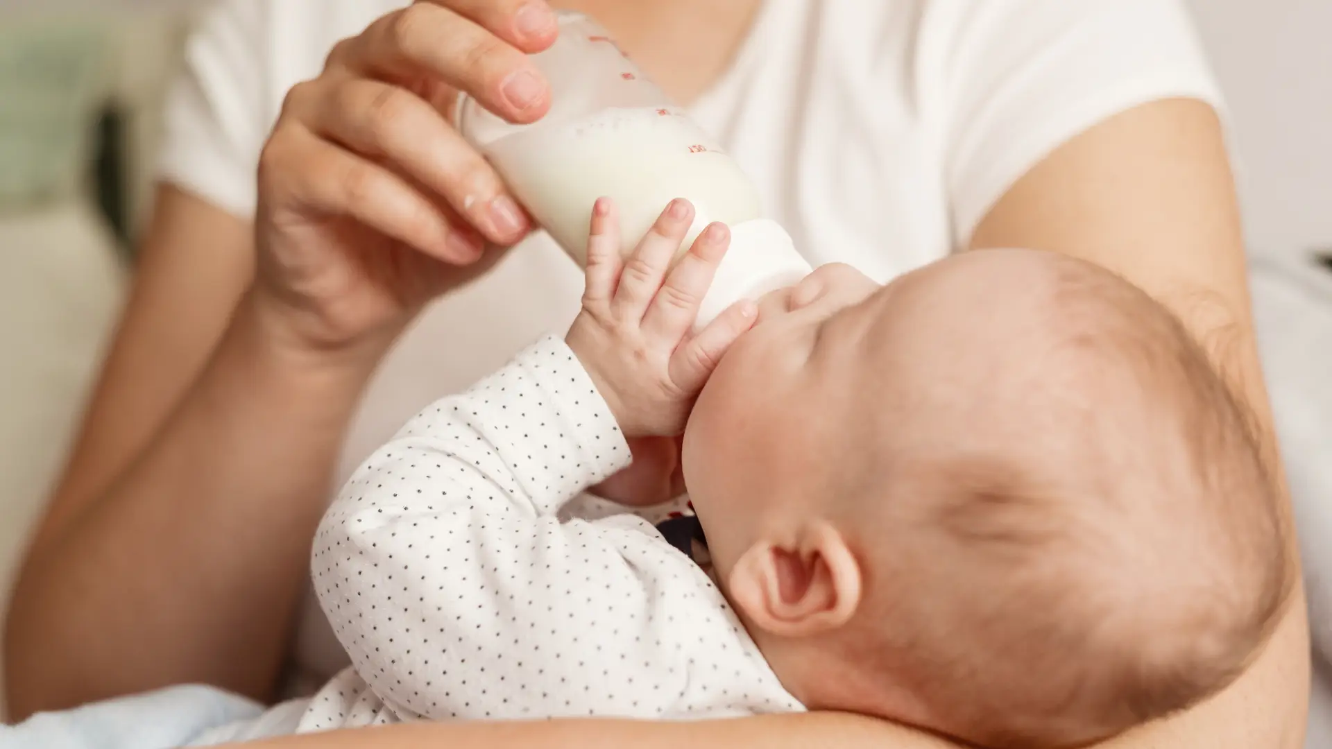 Un bebé toamando un biberón de leche que es uno de los alimentos que favorece el sueño