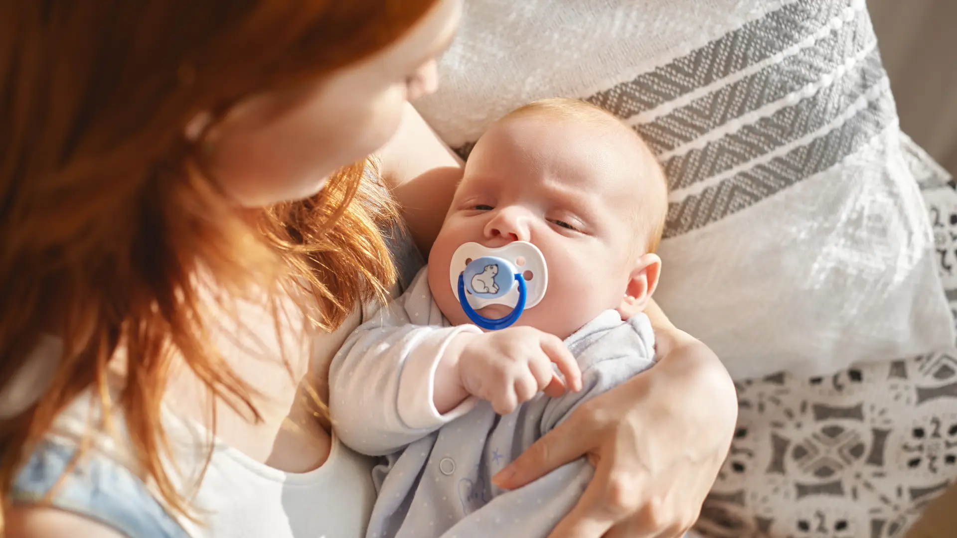 Una mamá con un bebé en brazos que esta utilizando la tecnica de como dormir al bebé