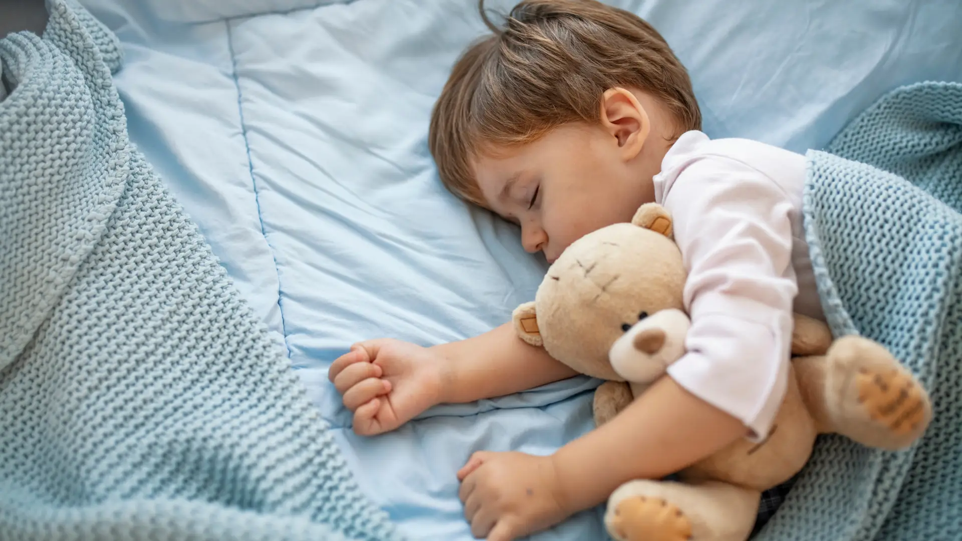 Un niño con su peluche durmiendo en los primeros dias del paso de cuna a cama 