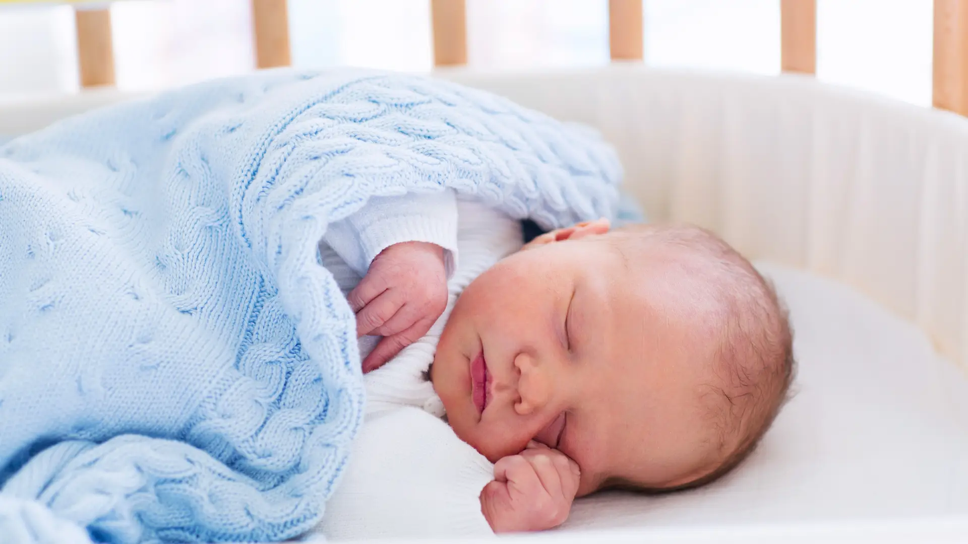 Un bebé dormido en la cuna al que su mama le pauta unas rutinas de sueño