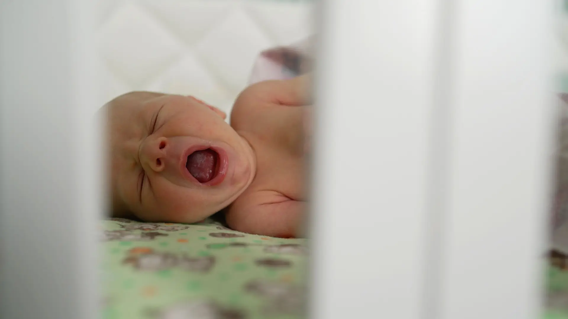 Un bebé bostezando en la cuna que es una de las señales de que tiene sueño